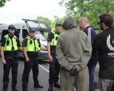 A row of police and face three men seen from the rear
