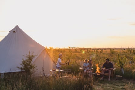 family outside a bell tent at summer sunset