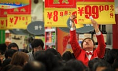 In this photo taken on Sunday, Feb. 20, 2011, a worker puts up a price list while customers buy groceries at a new supermarket in Chengdu in southwest China’s Sichuan province. Last week China ordered its banks to hold back more money as reserves in a new move to curb lending and cool a spike in inflation. (AP Photo)