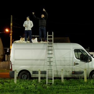 Watching the match on the top of a van parked outside the ground.