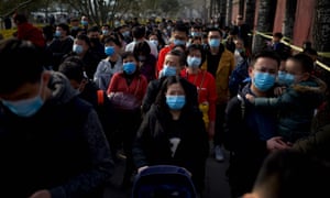 People wearing face masks queue to enter Tiananmen Gate in Beijing, China