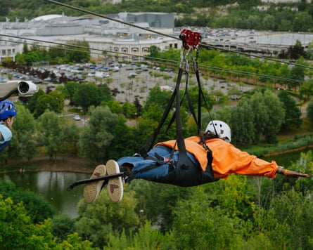 A person on zipwire with the Bluewater shopping centre in the background