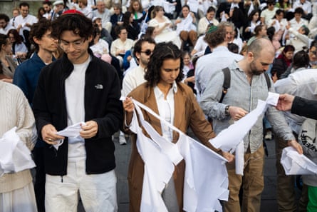 people in a crowd tear pieces of white fabric