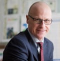 Andrew Morrish, with glasses and a shirt and tie, smiling