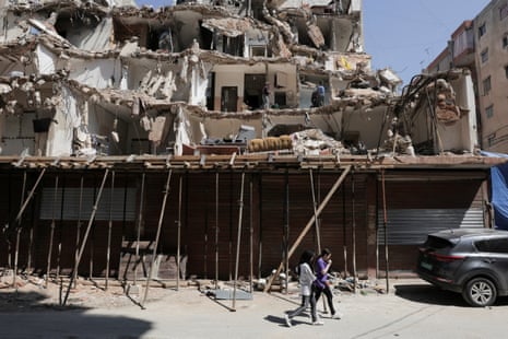 People walk in front of a damaged building in the southern suburbs of Beirut, Lebanon.
