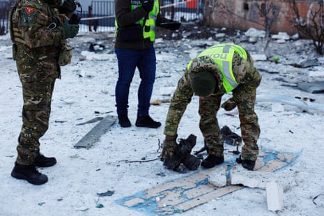 A police officer inspects a part of a Russian drone that was found at the site of an apartment building hit by one in Kyiv.