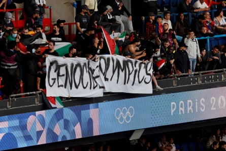 Supporters hold a banner reading “Genocide Olympics” in the men’s group D football match between Israel and Paraguay. Prosecutors said they were probing possible antisemitic hate crimes during the match