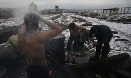 People wash themselves outside a makeshift shelter