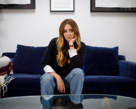 Keeley Hazell sits on a blue velvet sofa with her hand resting under her chin