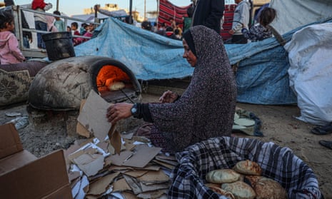 A displaced Palestinian woman bakes bread in Rafah in the southern Gaza Strip.