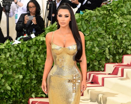Woman with long black hair and long gold dress posing for photo as she ascends stairs.