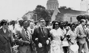 In May 1970, United Auto Workers president Leonard Woodcock, in glasses and dark suit, locks arms with Coretta Scott King and Joseph E Lowery as they lead a protest march in Atlanta.