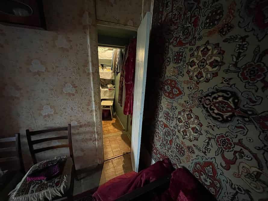 A small flat with old-fashioned wallpaper and a door open to show a pantry beyond.