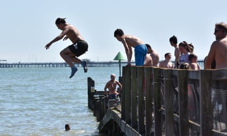 People jump from a jetty into the sea in Southend