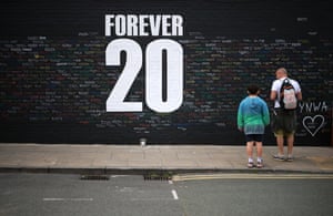 People look at tributes written on a memorial wall for Diogo Jota