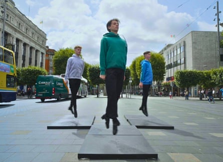 Three young male dancers dancing in a pedestrian area next to traffic.