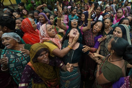 A woman at a funeral procession in India screaming and being held by other women