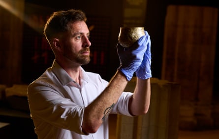 Dr Adam Parker holding up a silver-gilt bowl