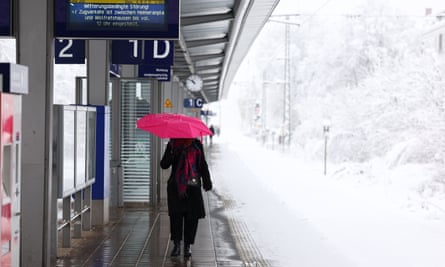 A woman walks along a train platform during heavy snow in Munich