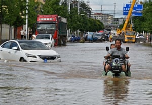 A man rides a motorcycle in a flooded street in Miyun district.
