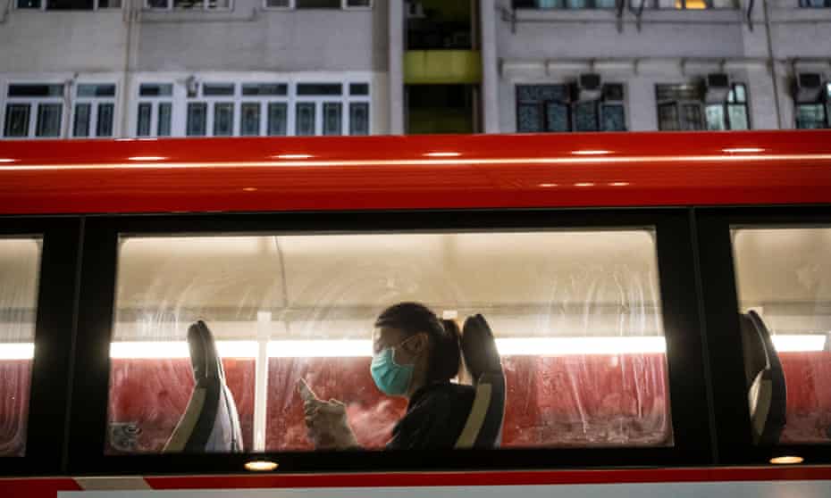 A passenger wearing a protective mask uses her phone on bus in Hong Kong
