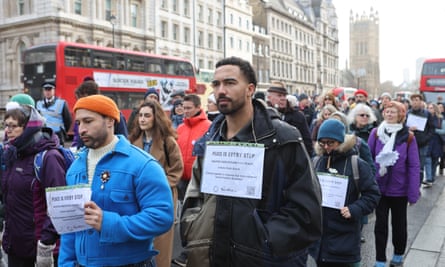 People walk down a London street holding signs with words under the heading ‘peace is every step’