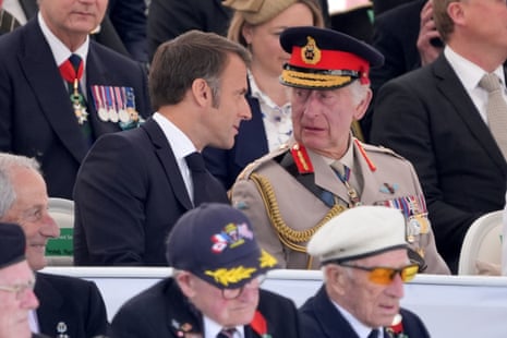 French president Emmanuel Macron is pictured speaking to King Charles as he takes his seat at British Normandy Memorial service.