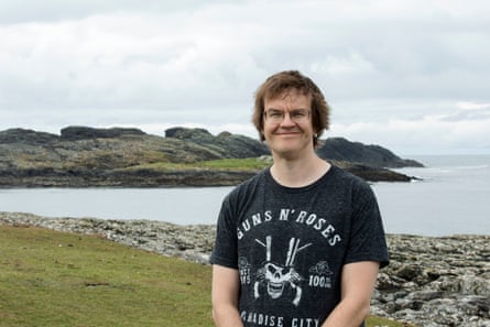 a man wearing a Guns N’ Roses T-shirt smiles outside