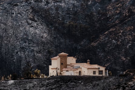 A house remains standing on a blackened and charred hillside