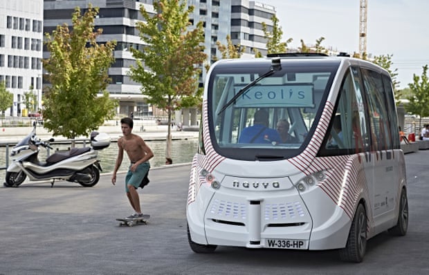 A skateboarder rides next to an electric driverless bus in Lyon, France.