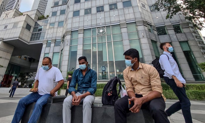 A group of men wearing masks sit on a bench in the financial district of Singapore, 16 February 2021.