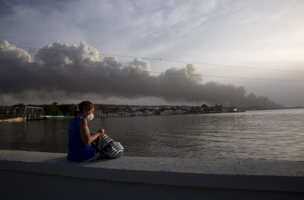 Ein Anwohner sitzt auf der Ufermauer des Malecon, während im Hintergrund der Rauch des Feuers aufsteigt. | Bildquelle: https://www.theguardian.com/world/2022/aug/10/cuba-fire-government-power-cuts © Ismael Francisco/AP | Bilder sind in der Regel urheberrechtlich geschützt