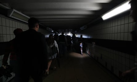 People walking in complete darkness at Clapham Junction station in London during a power cut.