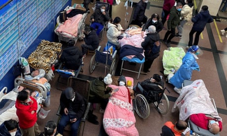 Patients lie on beds and stretchers in a hallway in the emergency department of a hospital in Shanghai