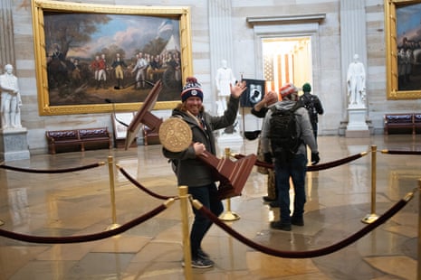 A pro-Trump protester carries the lectern of Nancy Pelosi through the Rotunda.