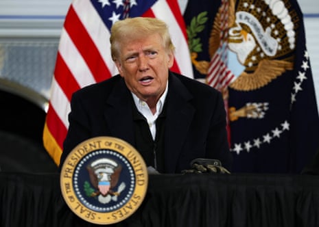 A man who is Donald Trump speaks at a podium in front of a US flag