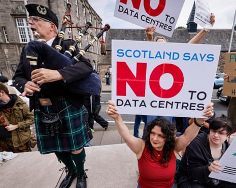 A bagpiper plays next to protesters holding signs reading 'Scotland says not to datacentres'.