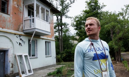 Harry Blakiston Houston, the founder of Insulate Ukraine, stands outside a damaged  apartment block with missing windows