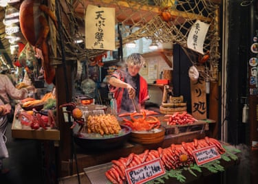 A street vendor surrounded by dishes in a crowded stall in Kyoto