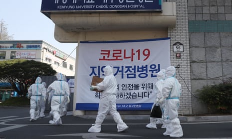 Medical workers wearting protective suits walk to work at a hospital in Daegu, South Korea