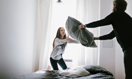 Jovem casal arrumando a cama em quarto bem iluminado (posado por modelos)