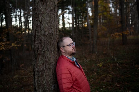 Man in red jacket leaning against a tree with his eyes closed