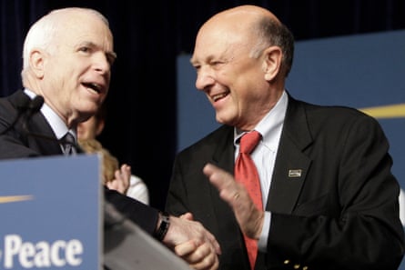 two men in suits smile on stage