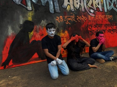 Sohan Mahmud, Humaira Fehrooz and Khuddho Ganguly perform kneeling alongside eachother, one in silver mask, one covering their eyes, the other their mouth