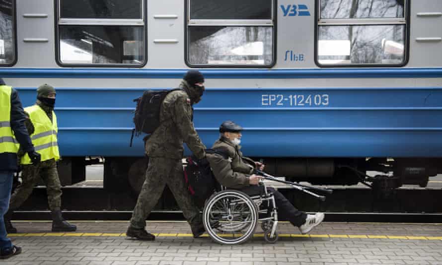 A soldier assisting a refugee from Ukraine in Przemysl, Poland.