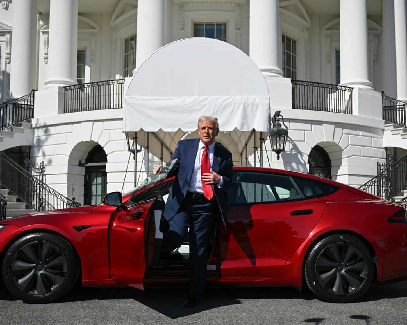 Trump Tesla: Musk Feud & Potential Sale – Live Updates Trump in front of a red Tesla.
