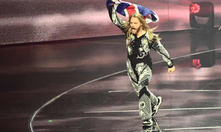 Sam Ryder walks across the stage in glittery jumpsuit at Eurovision, holding the union flag high