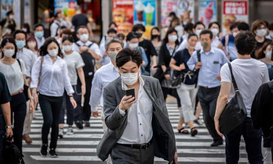 A man wearing a face mask crosses a street in Tokyo