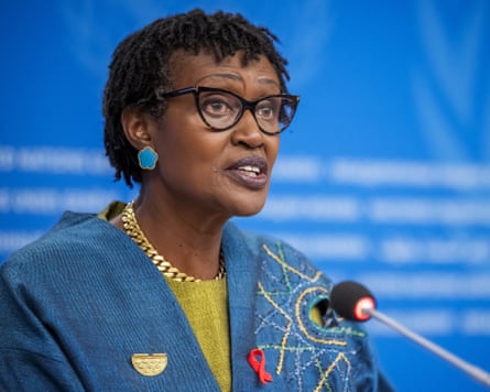 An older African woman at a lectern addressing an audience