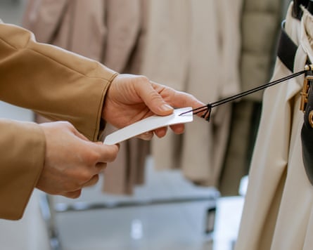 A woman’s hands holding a price tag in a clothing store.